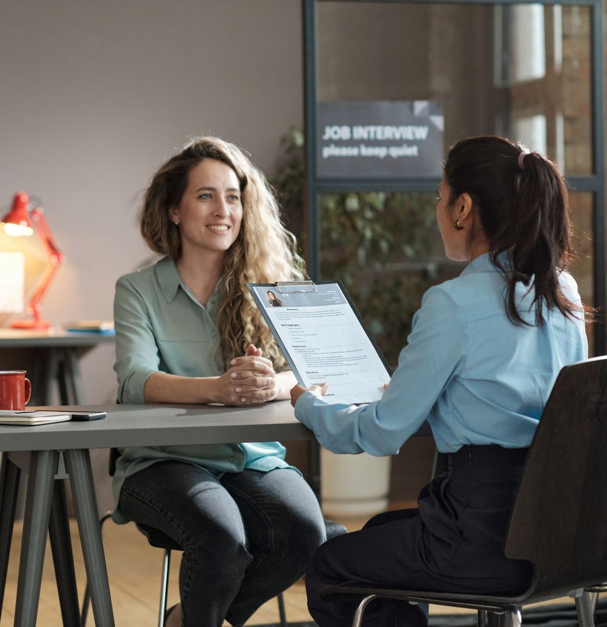 Two women are sitting at a table having a job interview