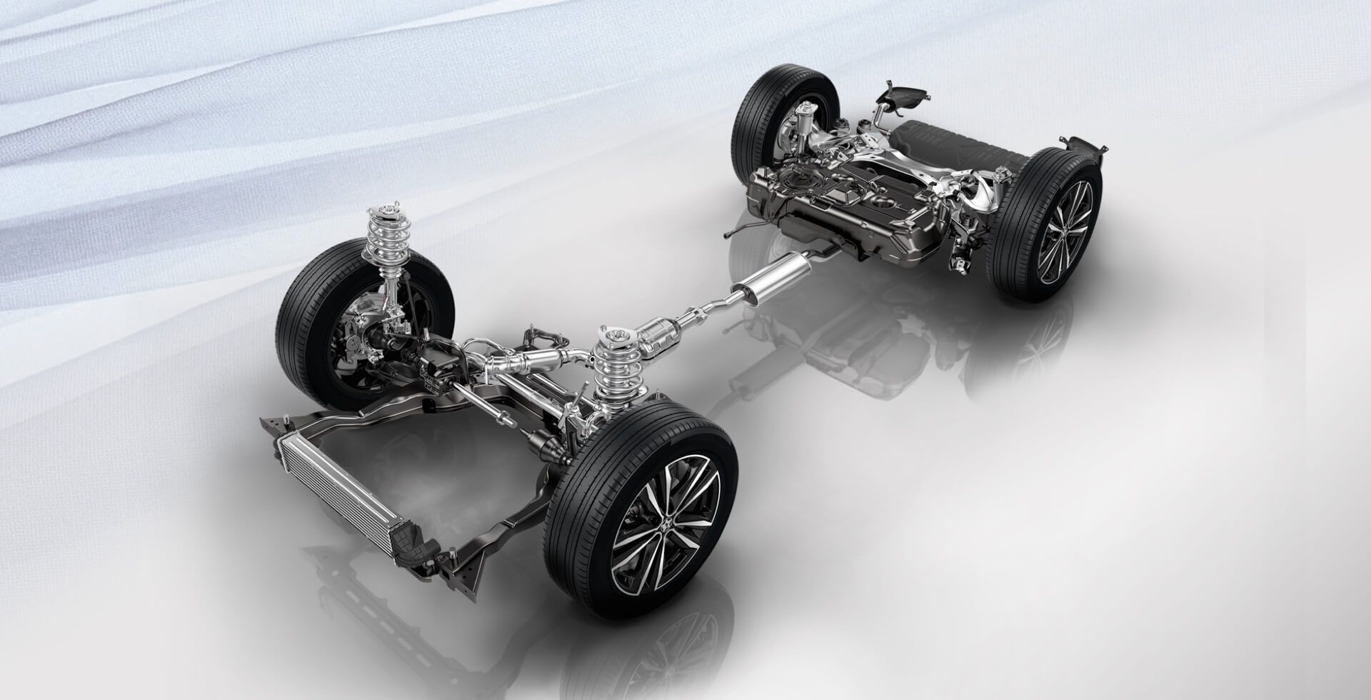 Car chassis, with wheels, suspension, and drivetrain components, on a light background.