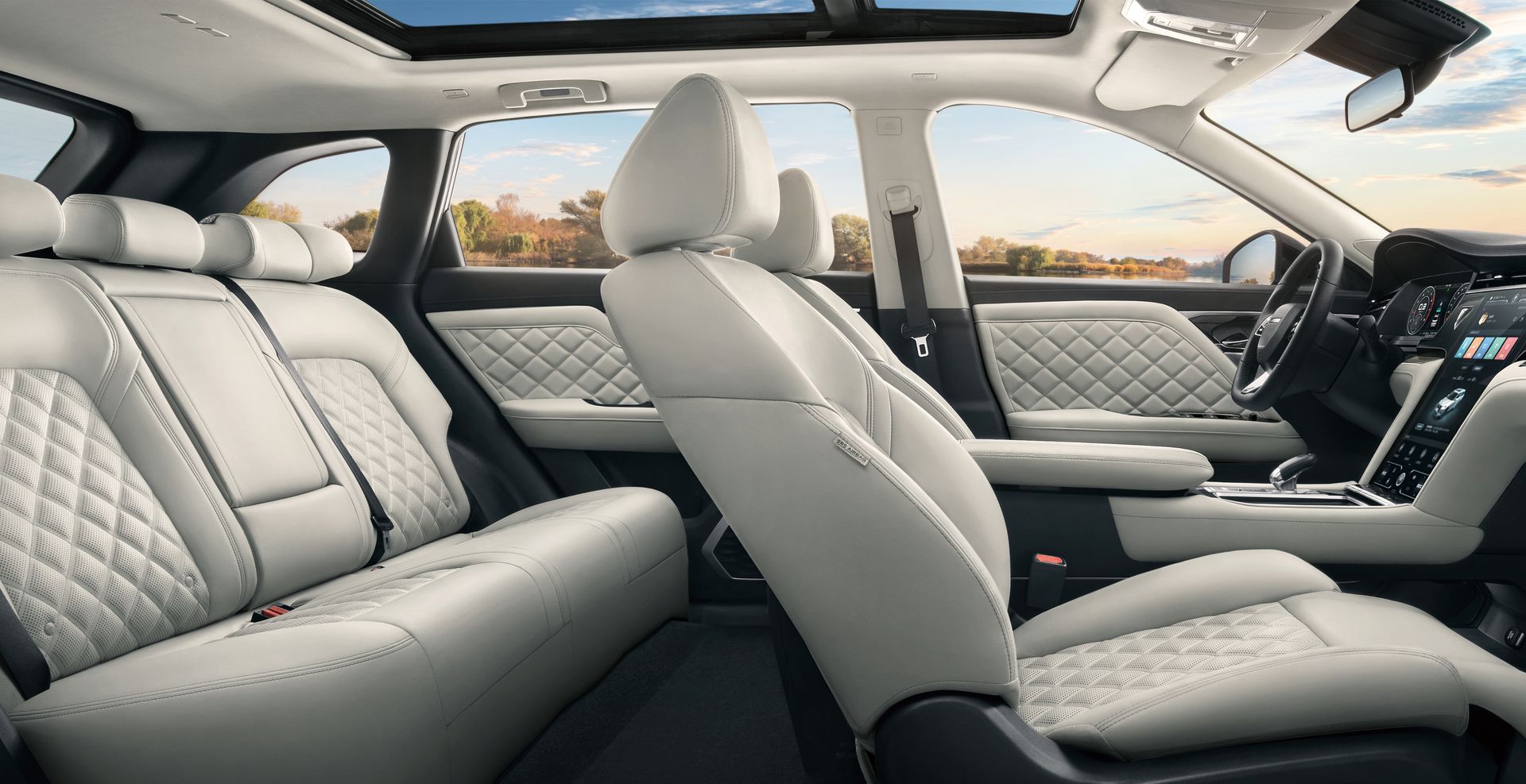 Interior view of a car with white quilted leather seats, a panoramic sunroof, and a view of a landscape.