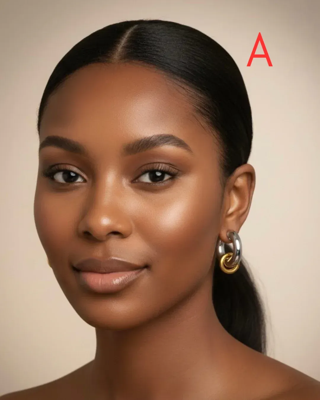 Woman with dark hair pulled back, wearing silver and gold hoop earrings, looking at the camera.
