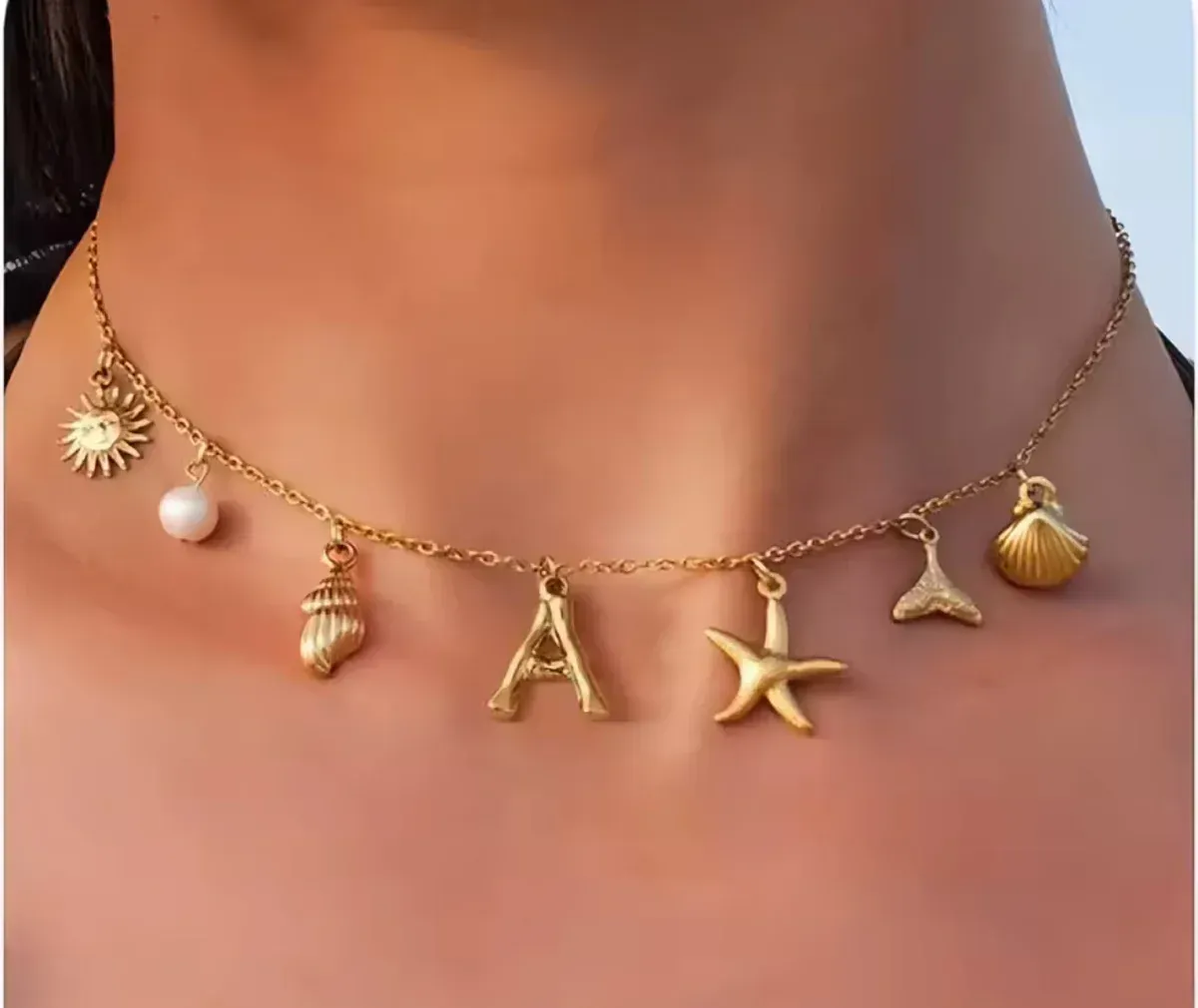 Gold charm necklace with sun, shell, pearl, letter 