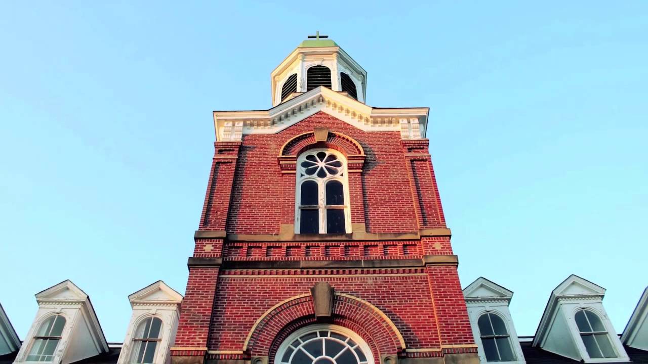 A large red brick building with a clock tower on top of it.