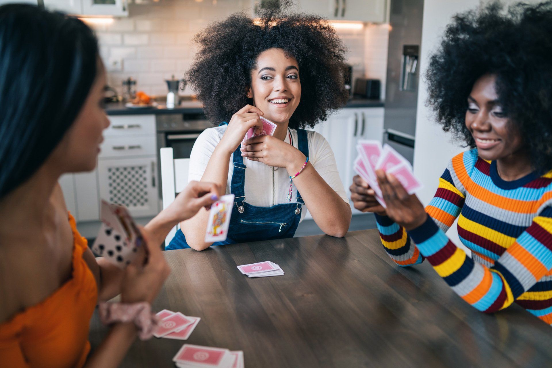 Three women are sitting at a table playing cards.