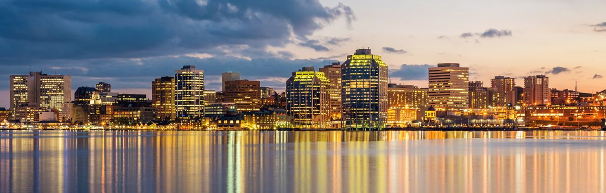 A city skyline is reflected in the water at sunset.