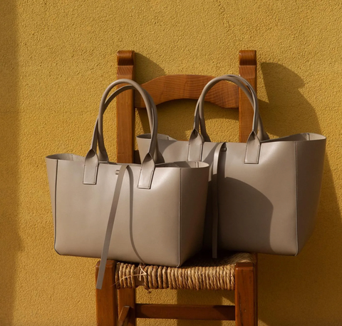 Two grey bags are sitting on a wooden chair