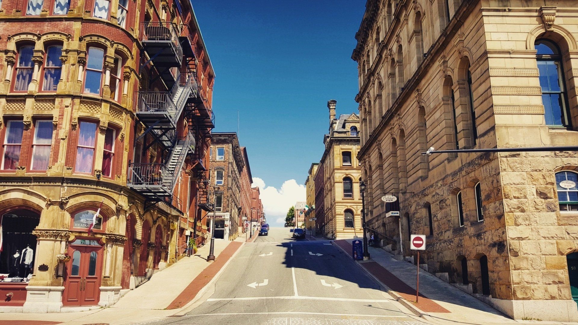 A city street with brick buildings and a no parking sign