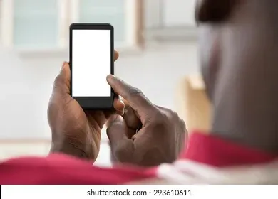 A man is holding a cell phone with a white screen.