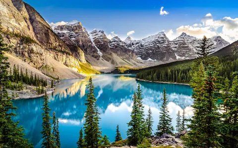 A lake surrounded by mountains and trees with a mountain in the background.