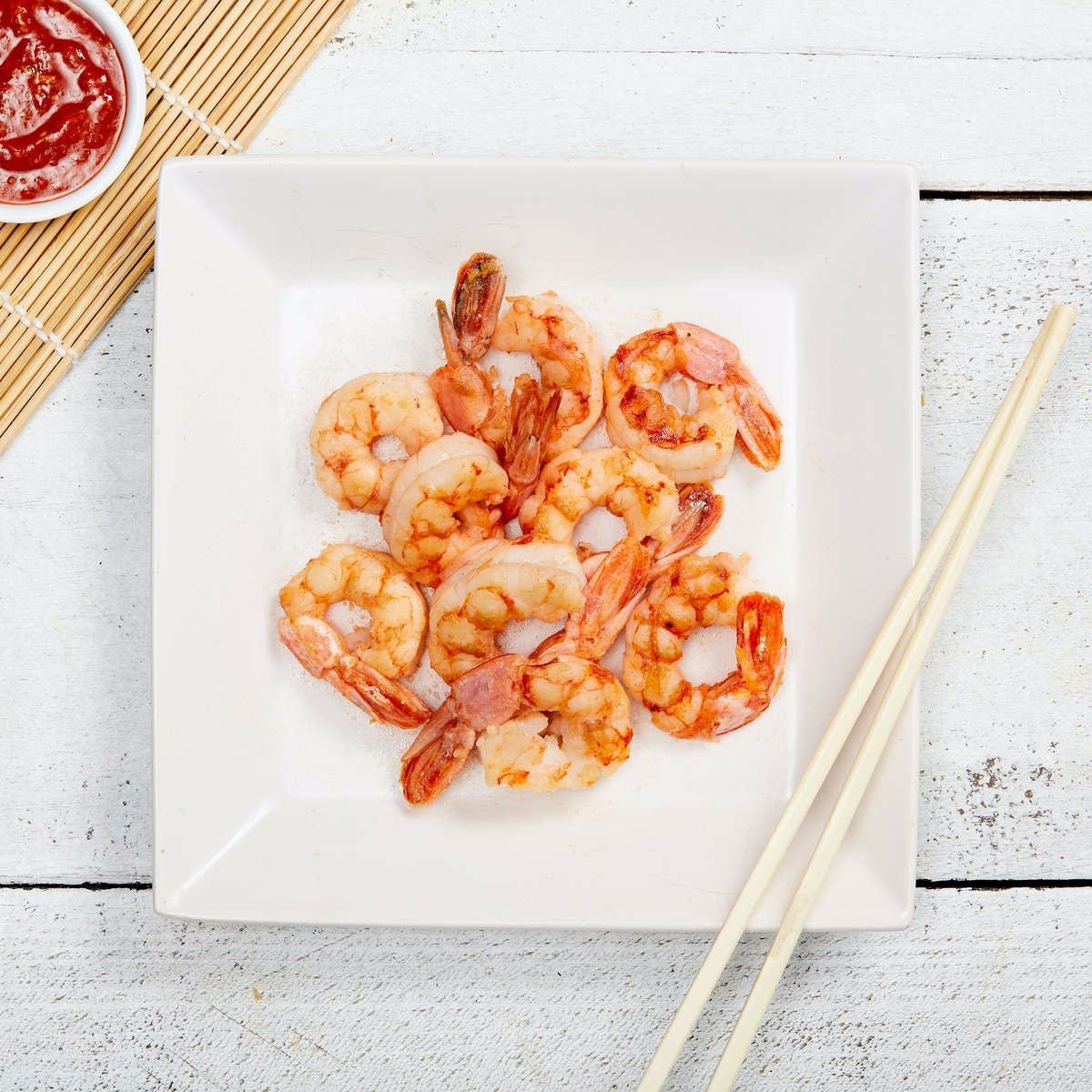 A white plate topped with shrimp and chopsticks