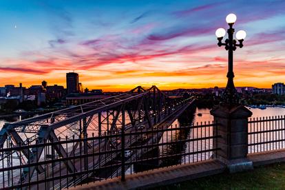 A bridge over a body of water with a sunset in the background.