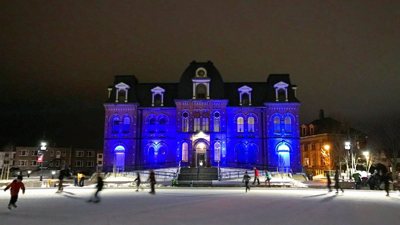 A large building is lit up with blue lights at night.
