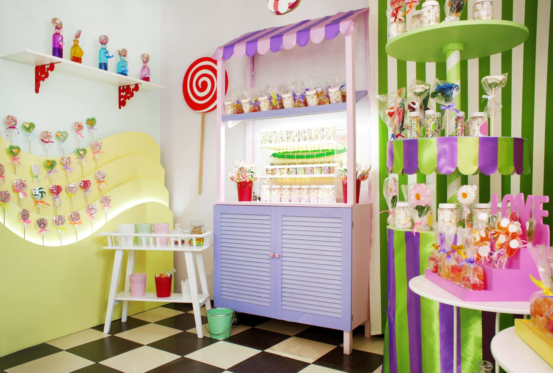 A room with a checkered floor and a candy cart filled with candy.