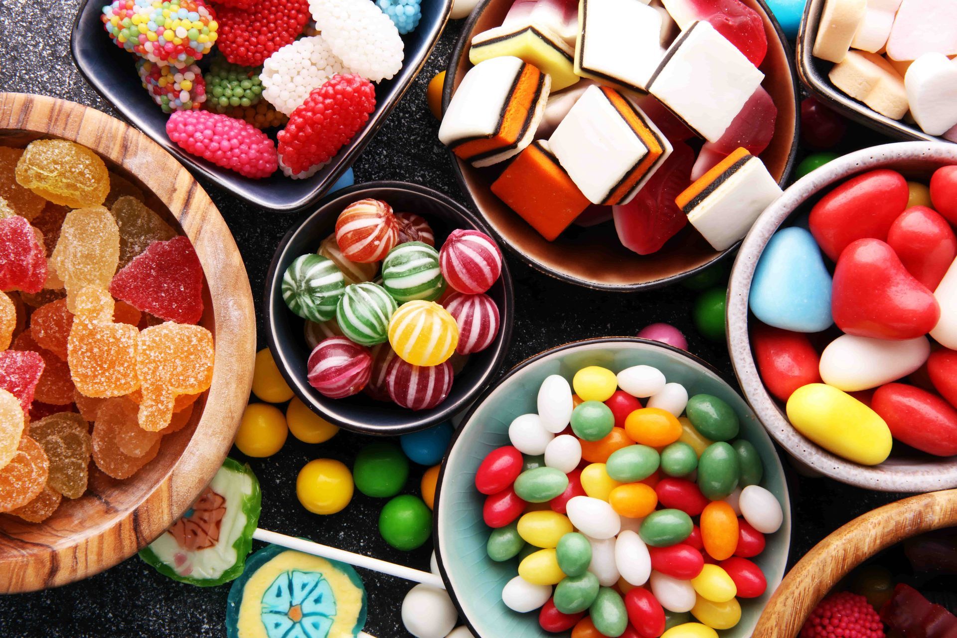 A variety of colorful candies in bowls on a table.