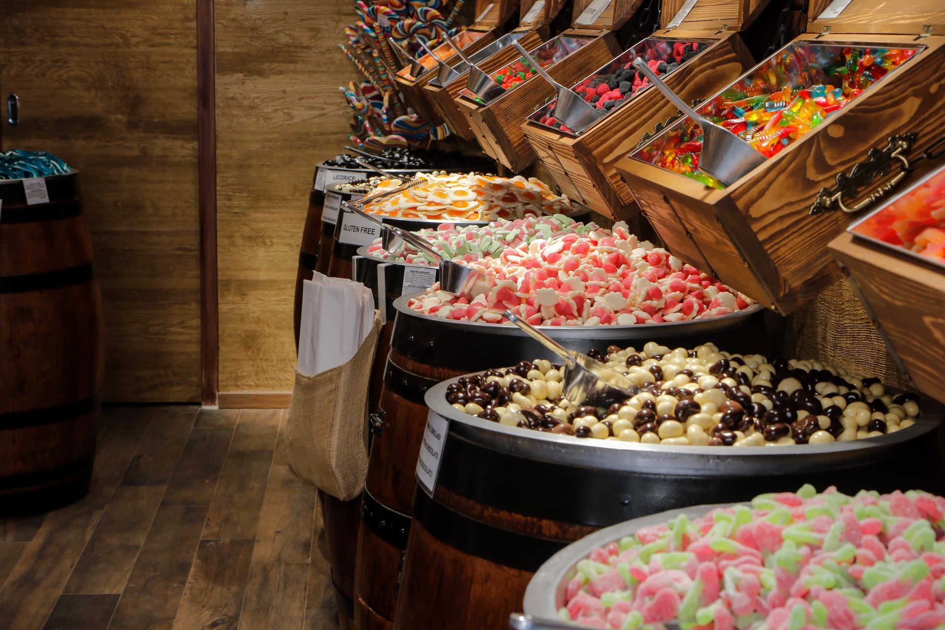 A row of wooden barrels filled with different types of candy.