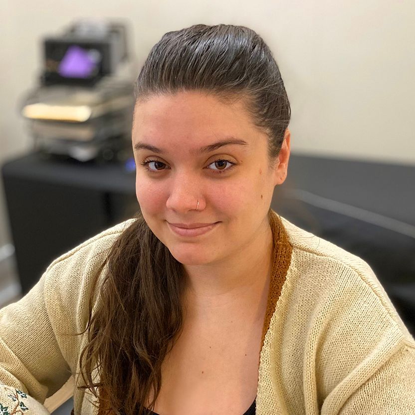 A woman in a tan sweater is smiling for the camera.