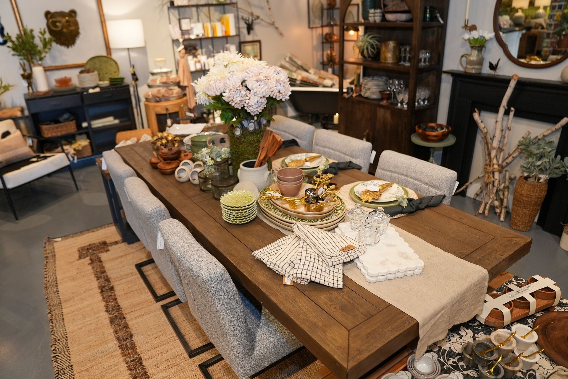 A wooden dining table set for eight, with a floral centerpiece in a store.
