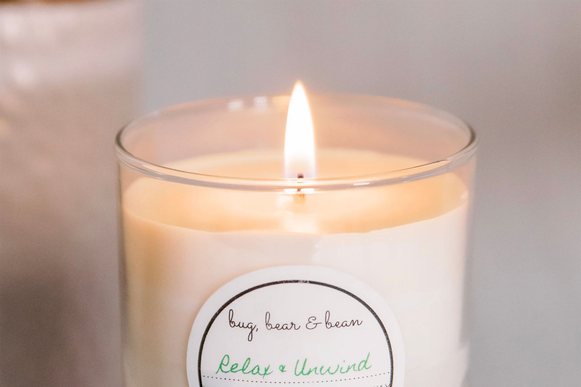 Lit candle in a glass jar, white wax with a label reading 