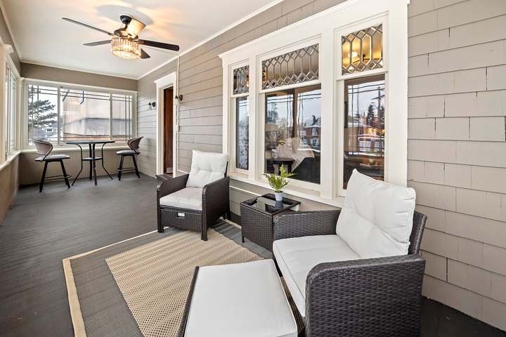 A porch with a couch , chairs and a table with a ceiling fan.