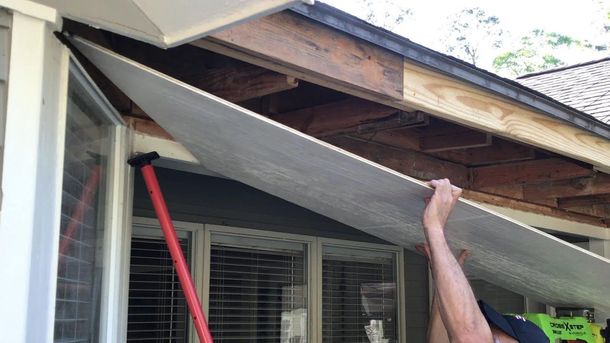 A man is holding a piece of wood over his head