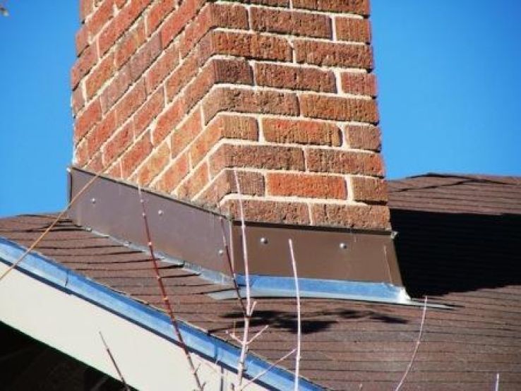 A brick chimney on top of a brown roof