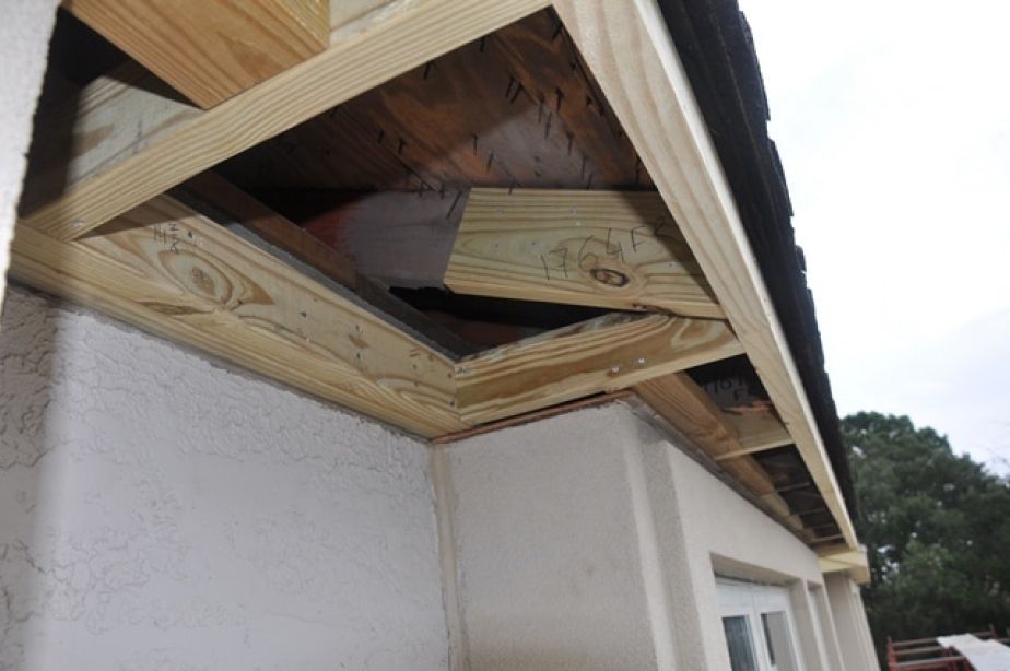 A wooden beam is being installed on the side of a building