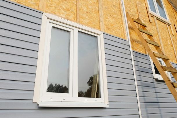 A window is being installed on the side of a house.