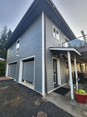 Modern gray home with freshly painted siding, trim, and garage doors