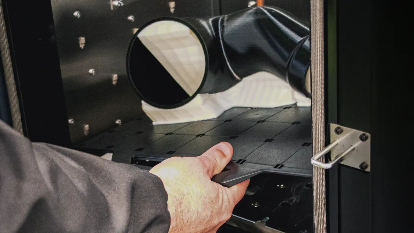 A hand adjusting automotive parts inside a 3D printer.