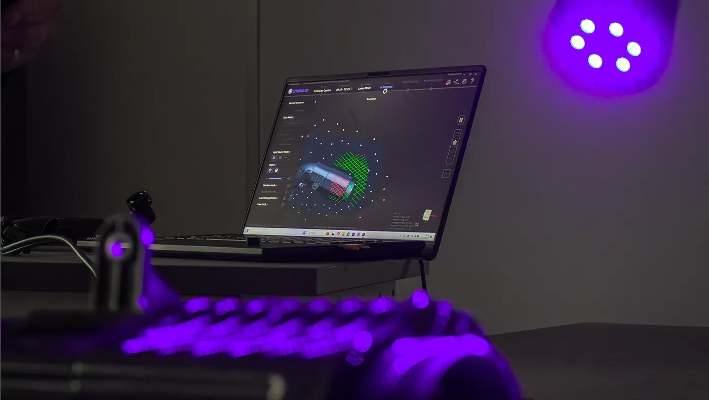 The process of 3D scanning is being demonstrated on a laptop with a scanning device in focus.