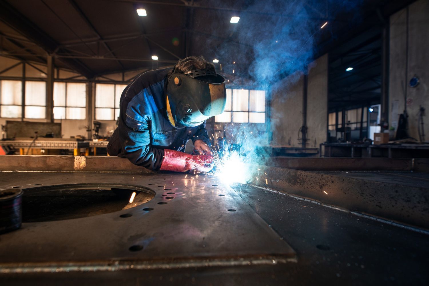 Material Processing - A skilled worker welding with sparks flying in a manufacturing environment.