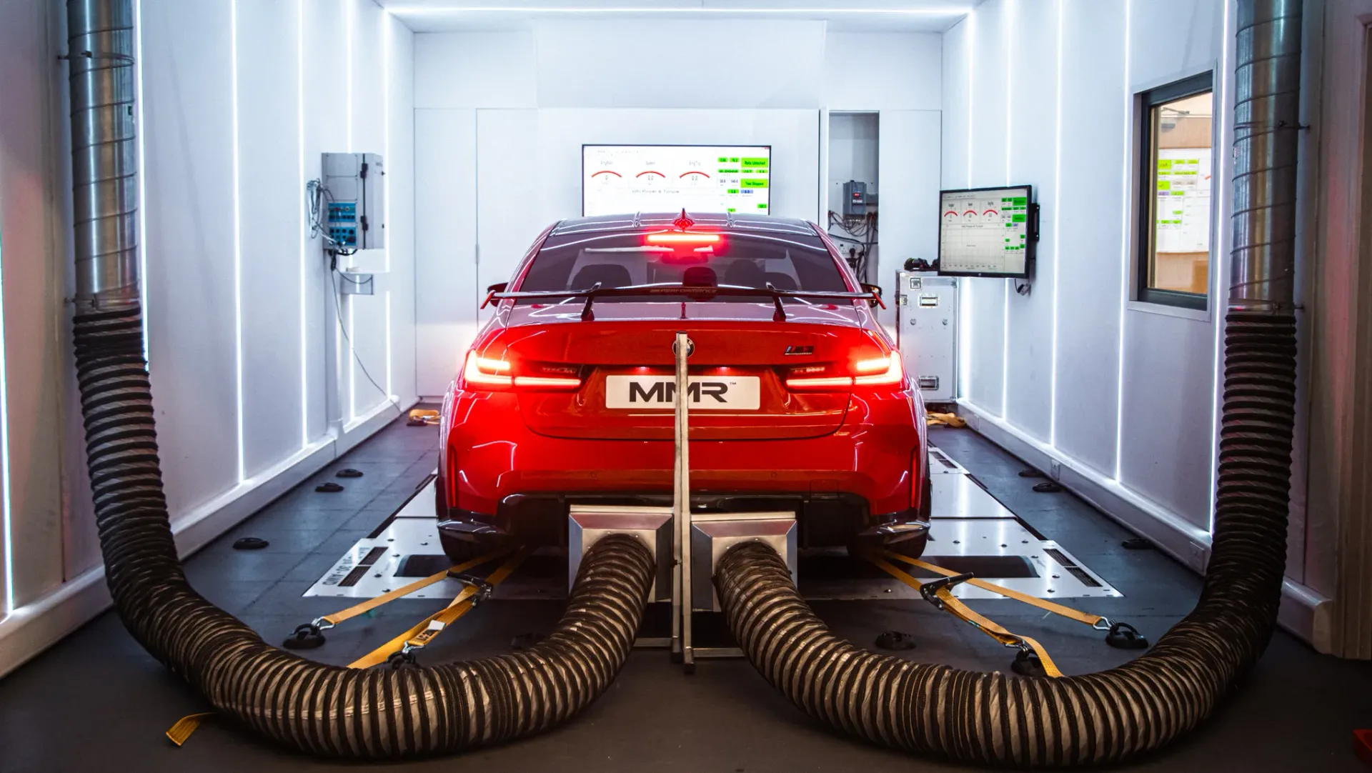 A close-up view of a red vehicle connected to a dynamometer for performance testing.