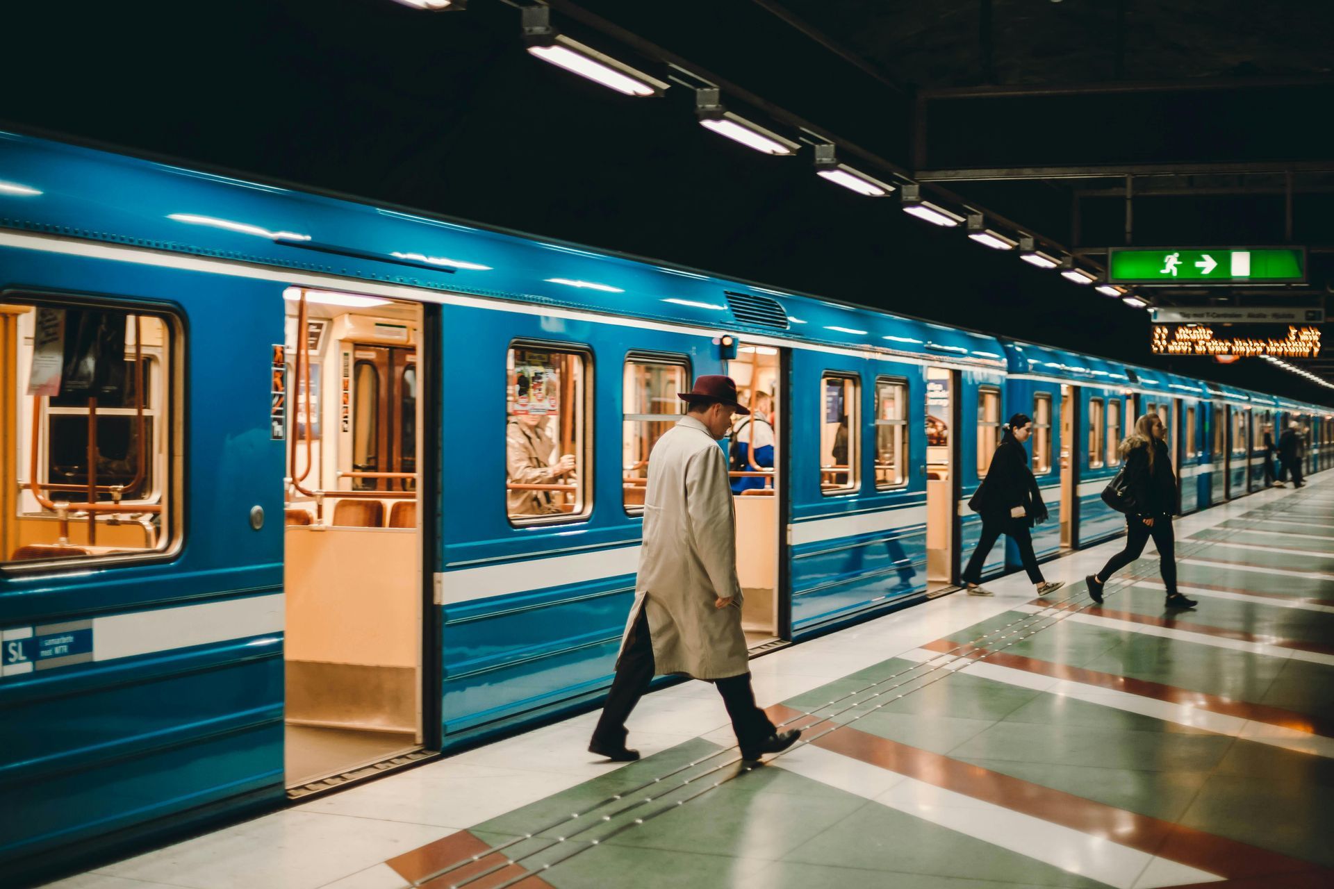 Commuters entering and exiting a blue train at a station.