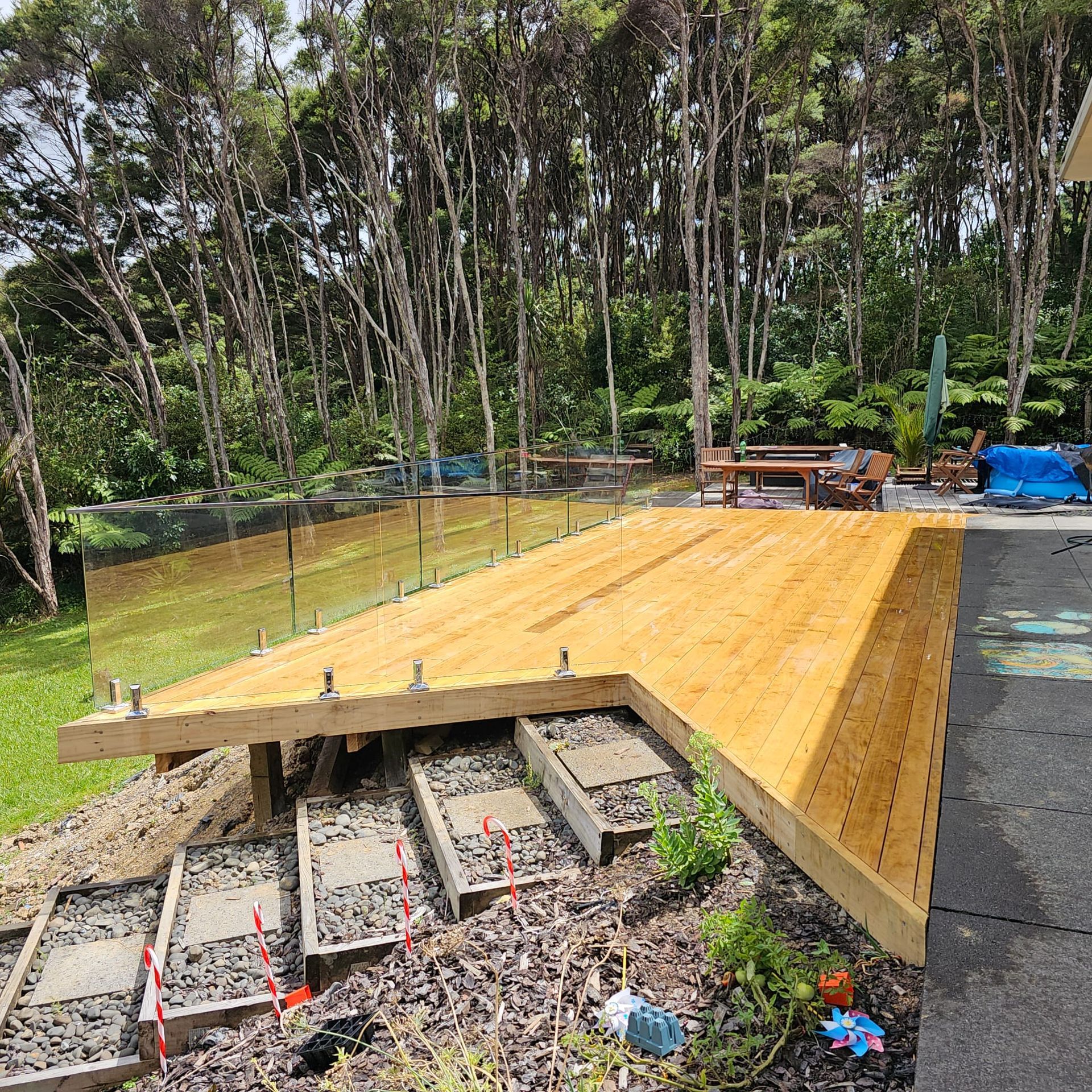 A wooden deck is being built in a backyard with trees in the background.