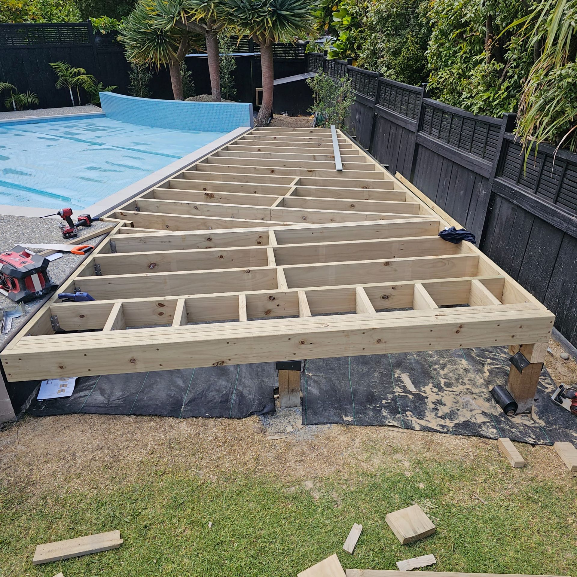 A wooden deck is being built next to a pool.