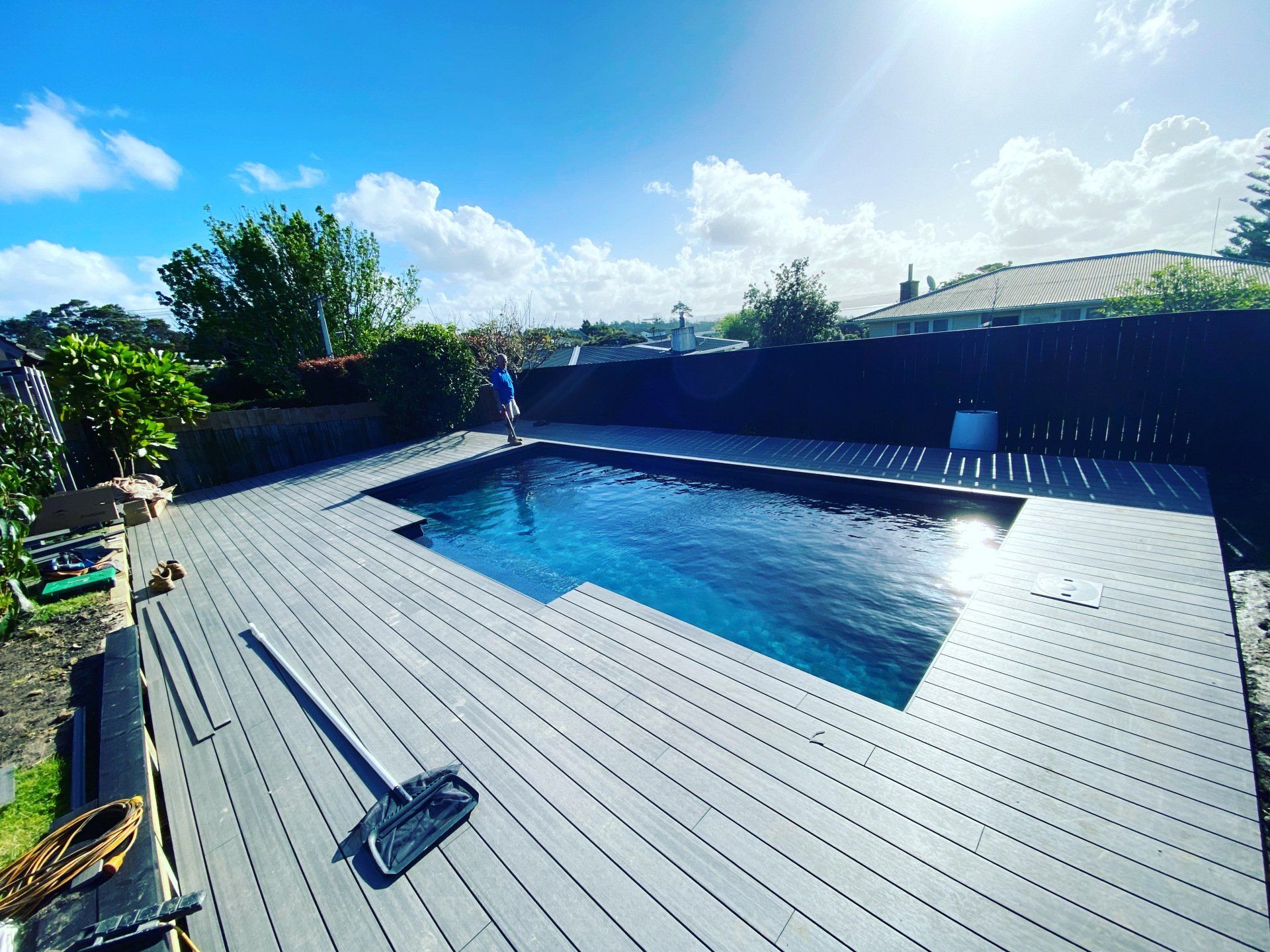 A large swimming pool is surrounded by a wooden deck.