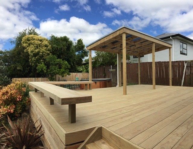 A wooden deck with a pergola and a bench