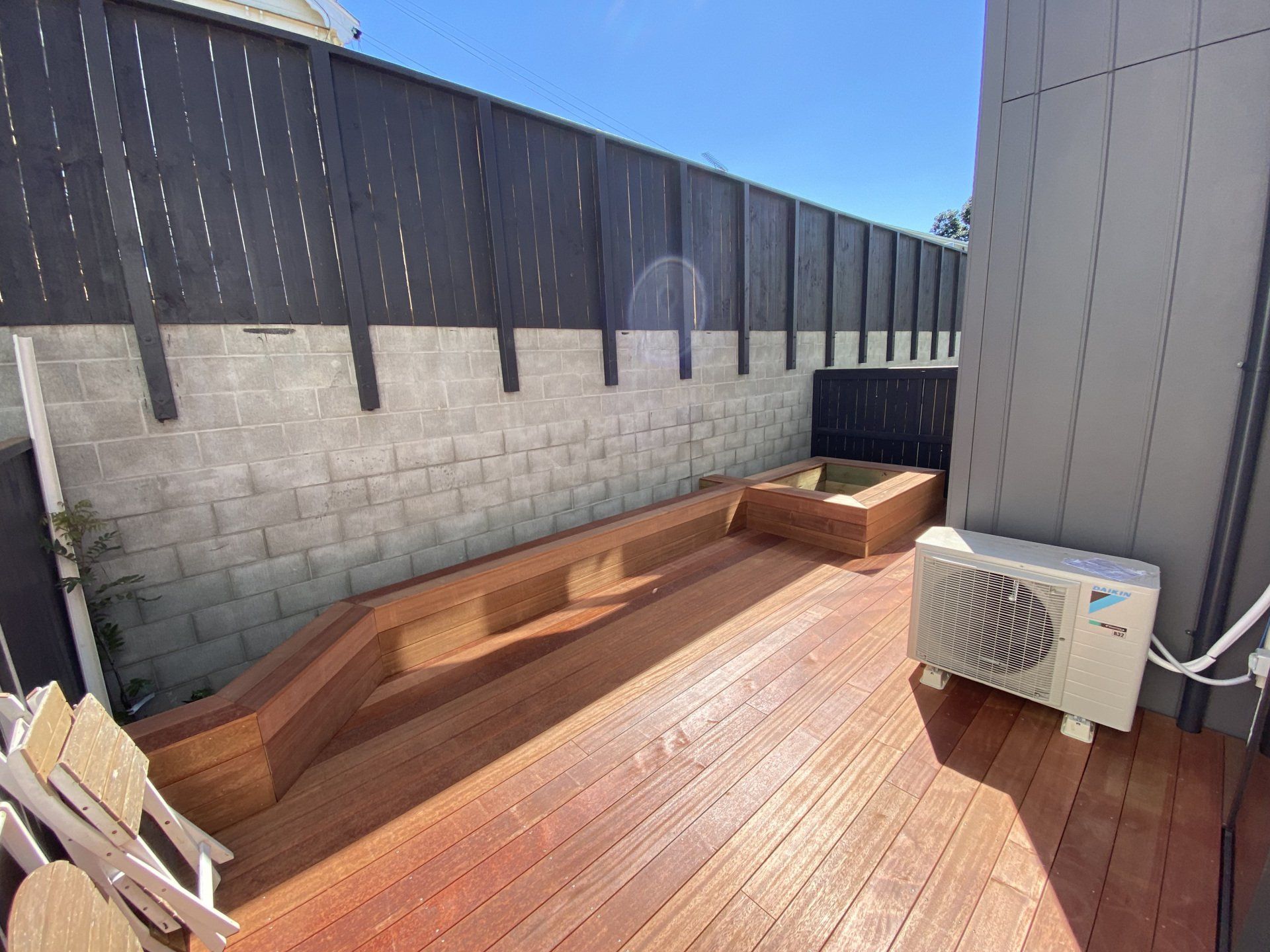A wooden deck with a bench and a fan on it.