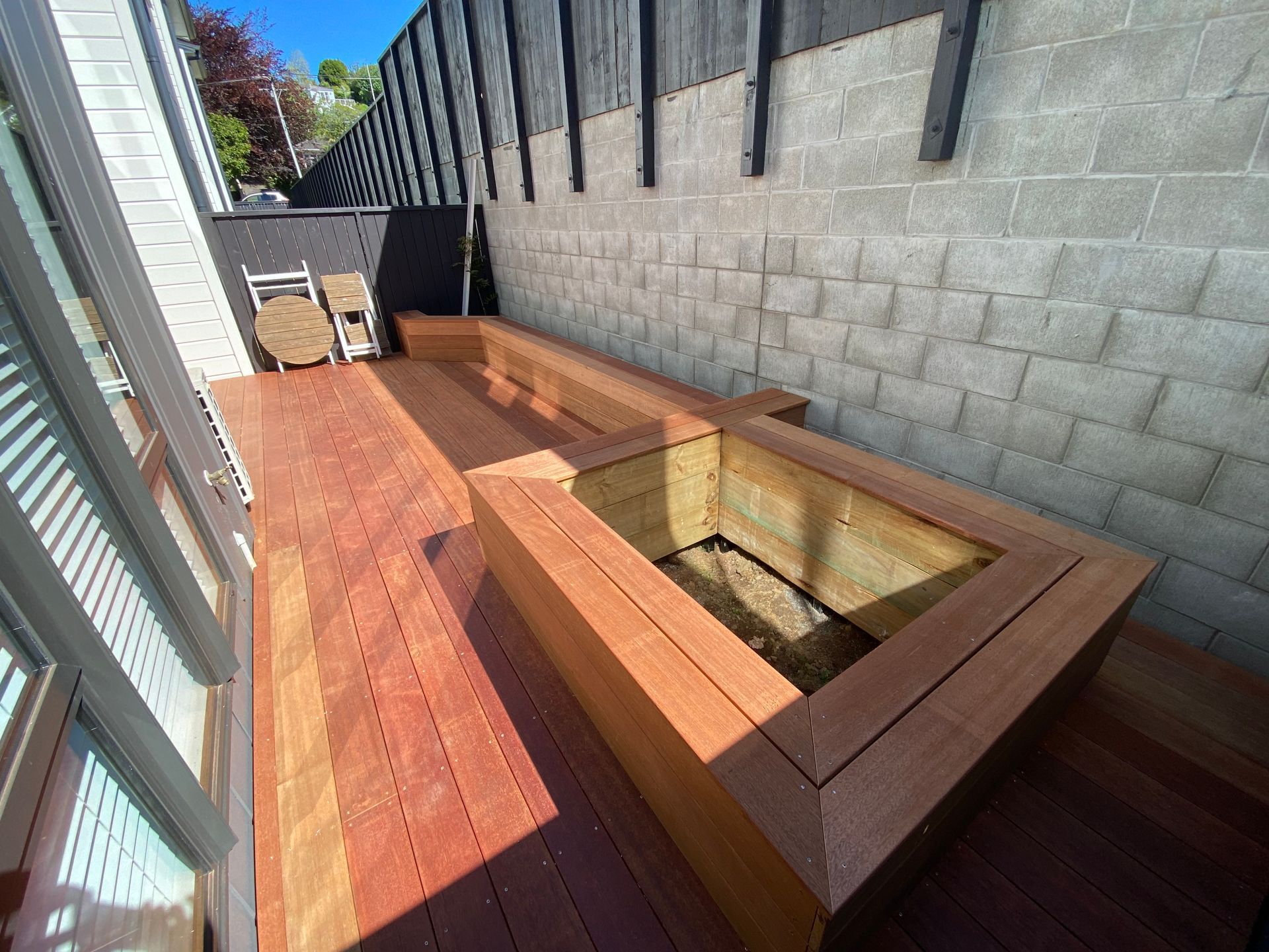 A wooden deck with a bench and a brick wall behind it.