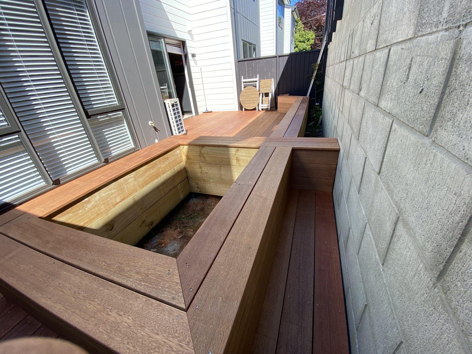 A wooden deck with a brick wall in the background