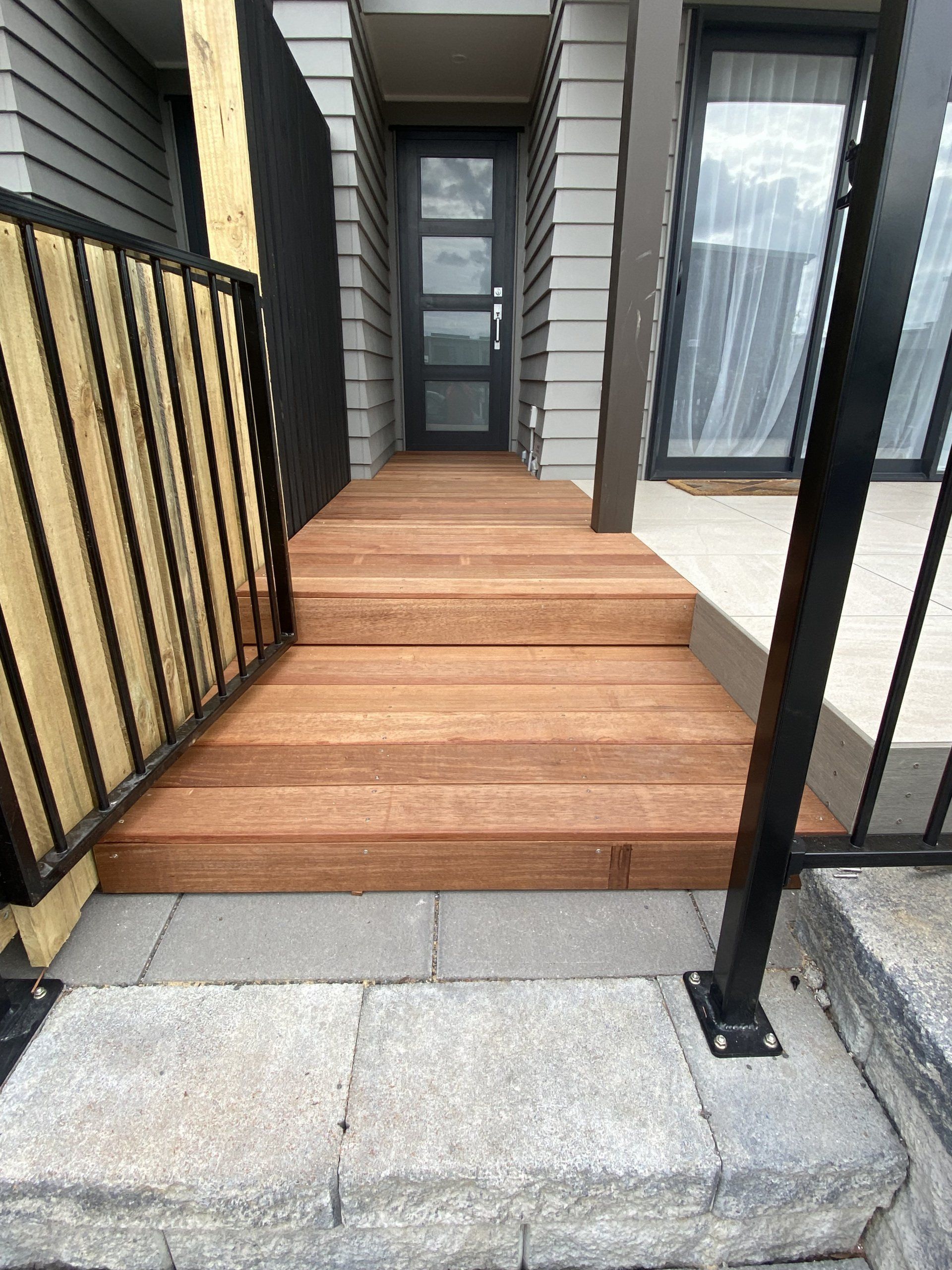 A wooden walkway leading to the front door of a house.