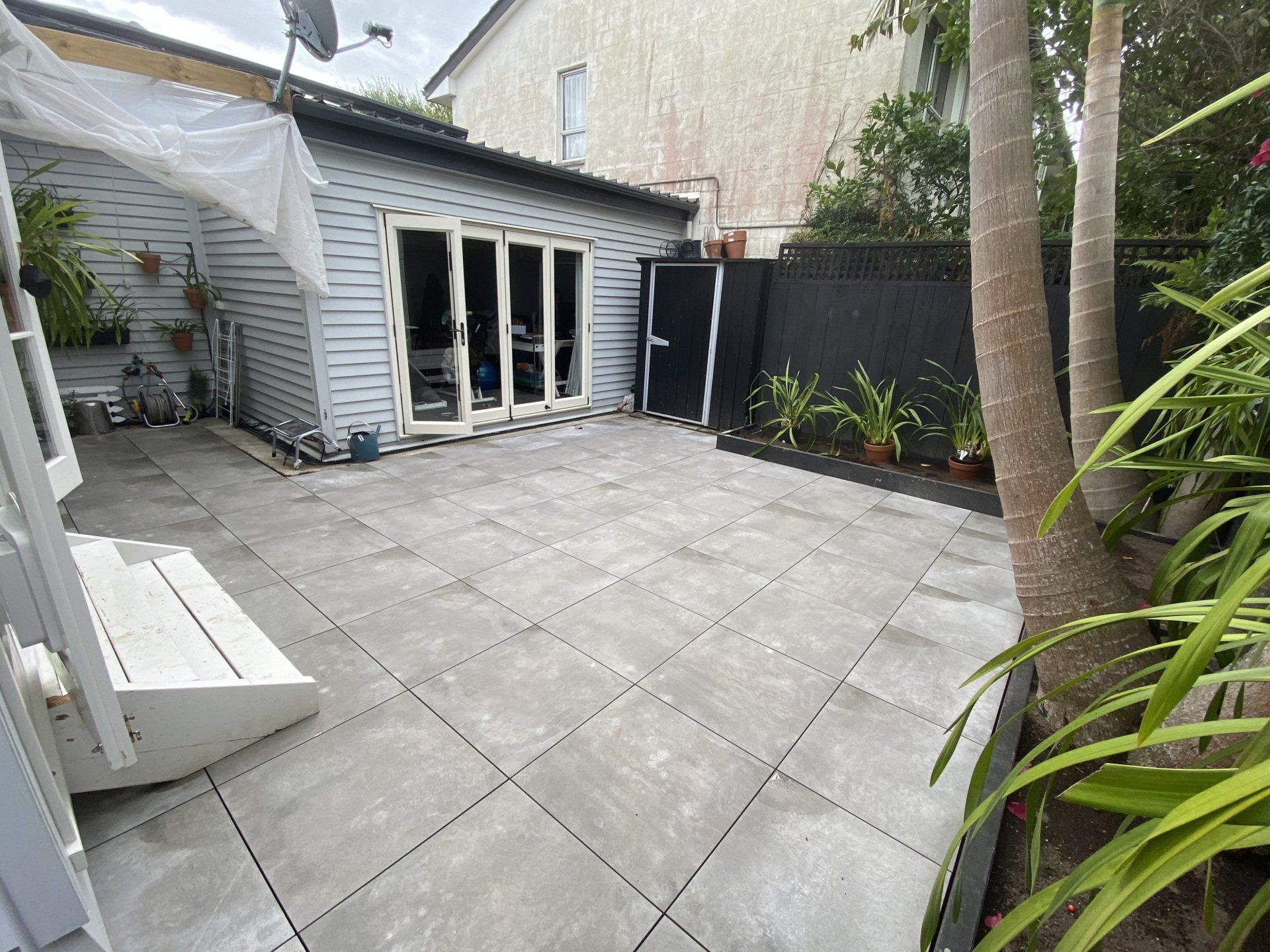 A backyard with a patio and a house in the background.