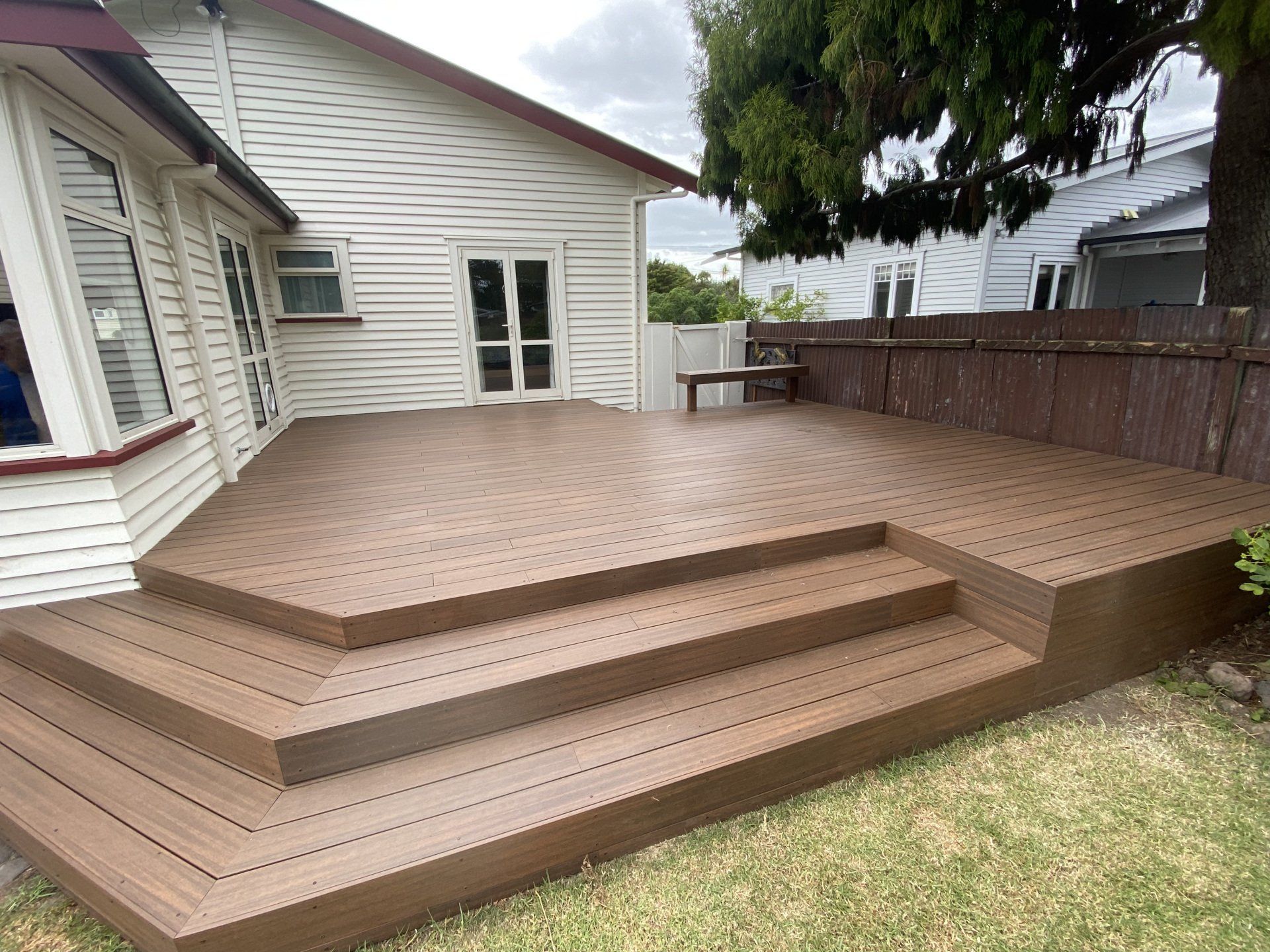 A wooden deck with stairs is in front of a house.