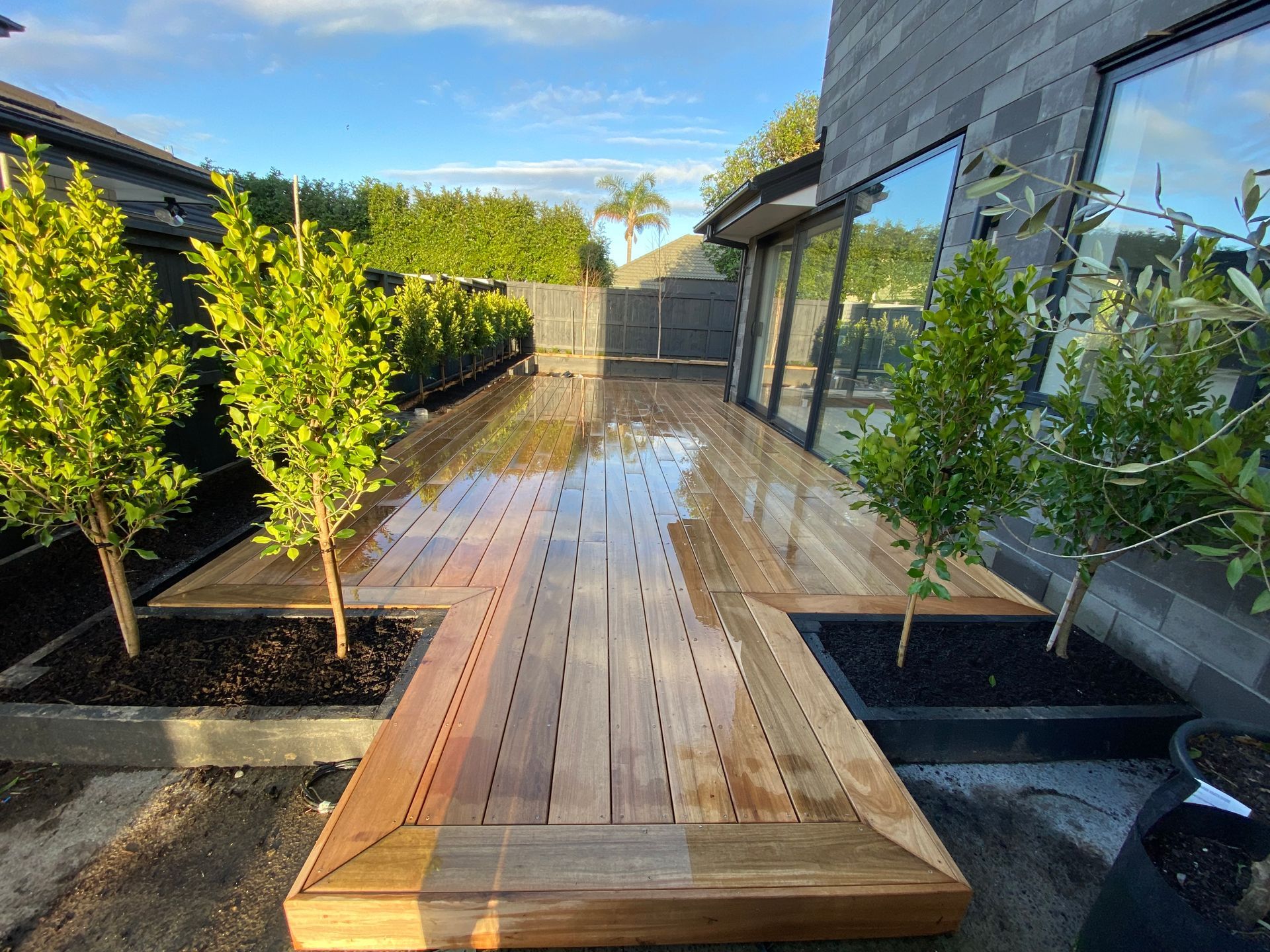A wooden deck with trees and bushes in front of a house.
