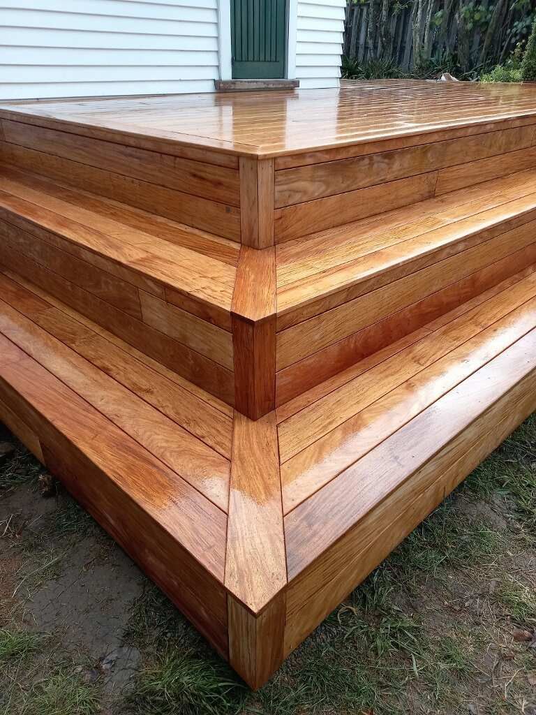 A wooden deck with stairs and a white house in the background.