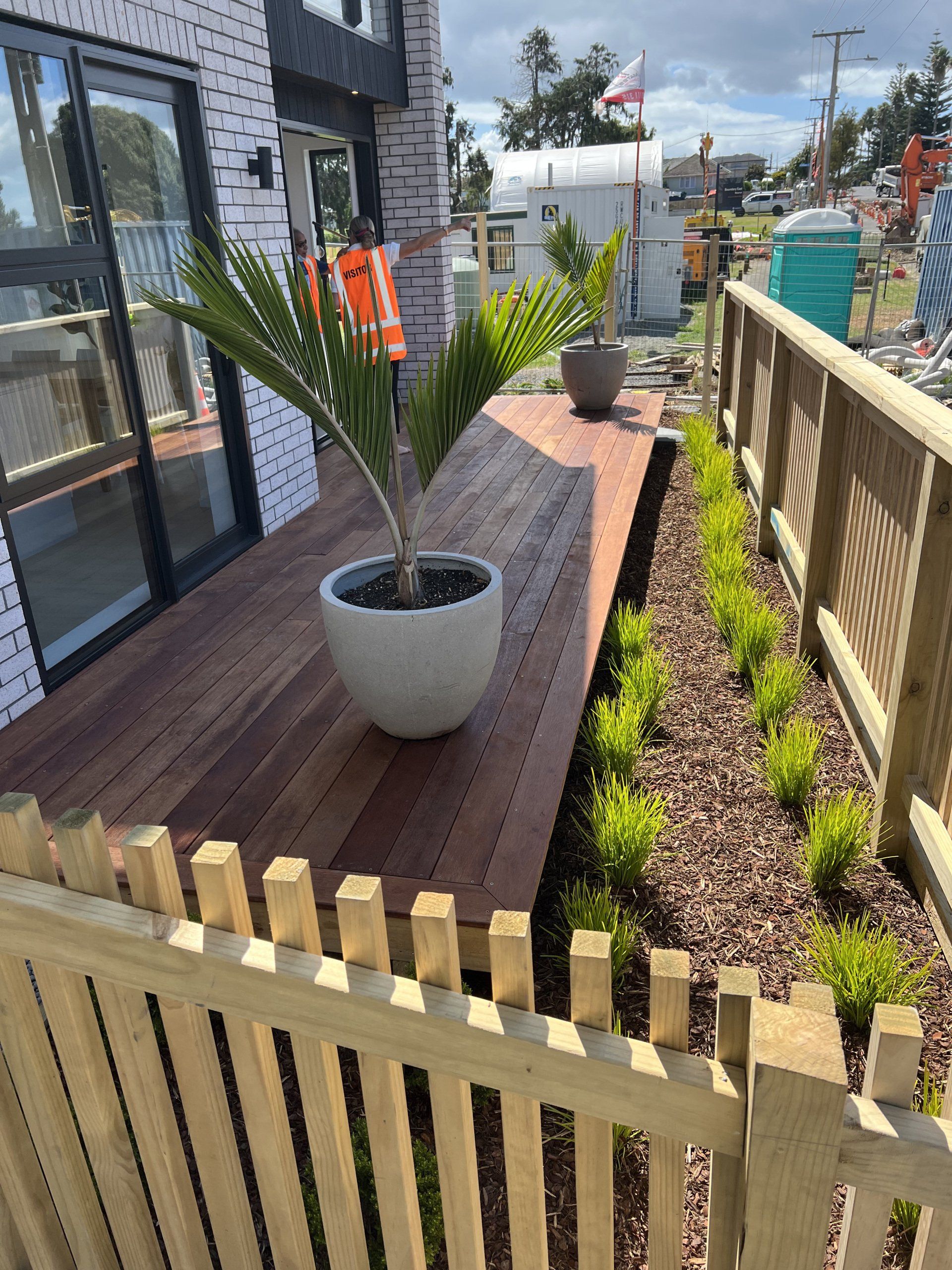 A potted plant is sitting on a wooden deck next to a wooden fence.