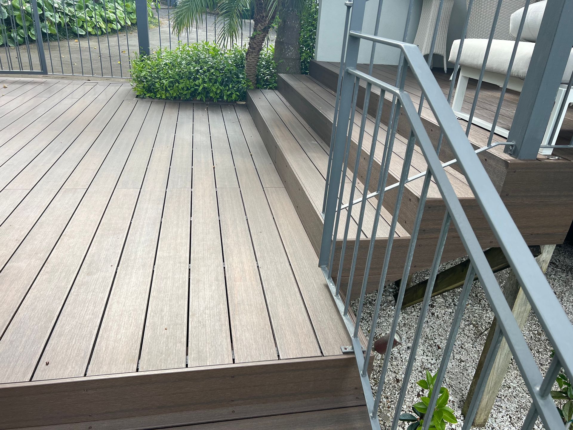 A wooden deck with stairs and a metal railing
