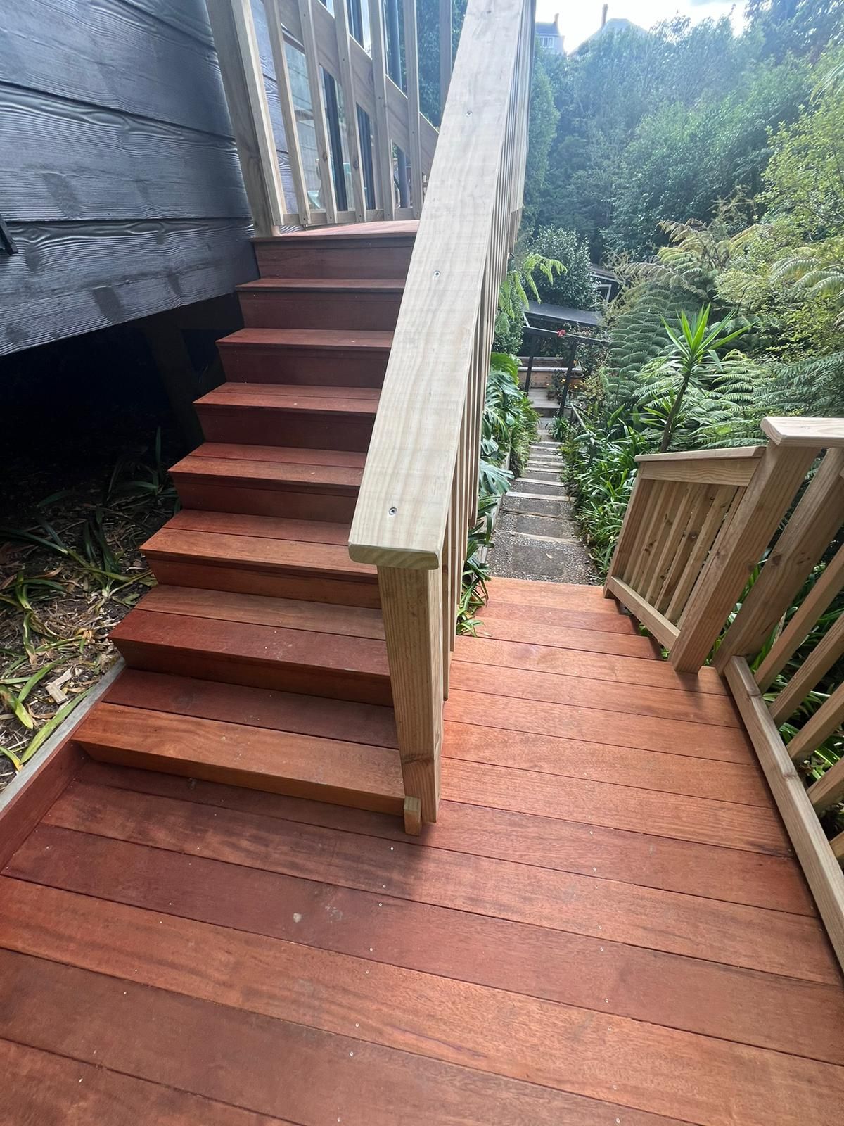 A wooden deck with stairs leading up to a house.