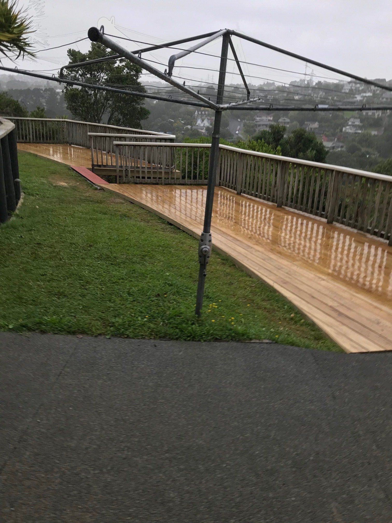 A clothes line is sitting on top of a lush green lawn next to a wooden deck.