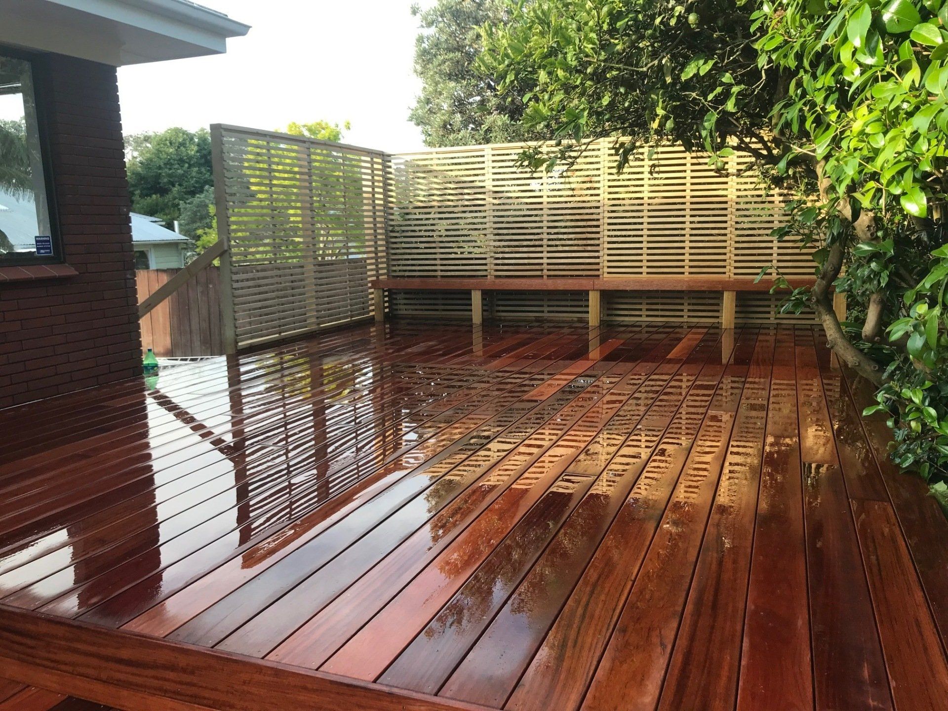 A wooden deck with a bench and a fence in the background