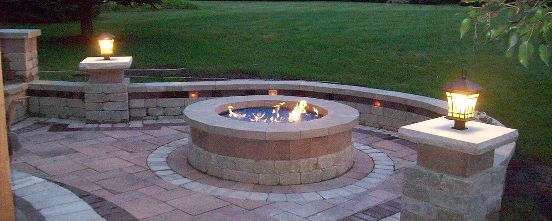 a fire pit is lit up at night in a backyard .